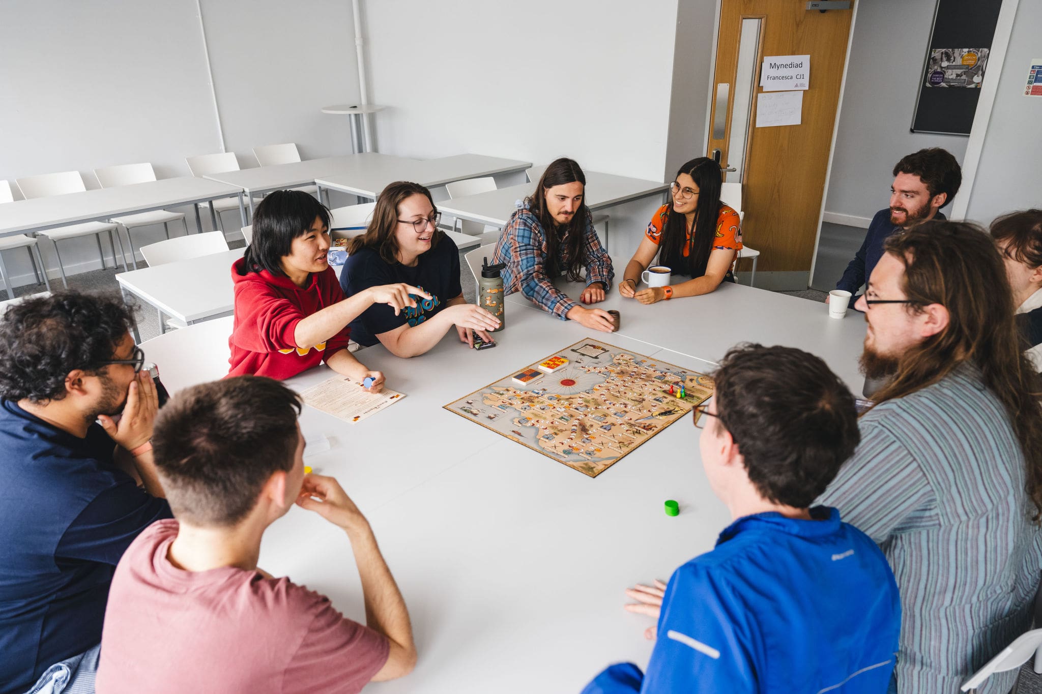 A group of young people sitting round a table playing a board game